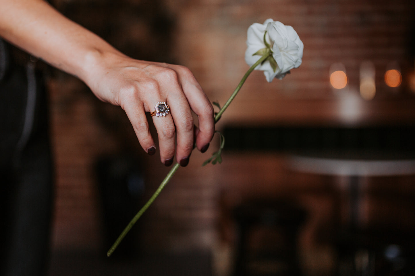 Black stone ring on woman's hand, holding a white flower