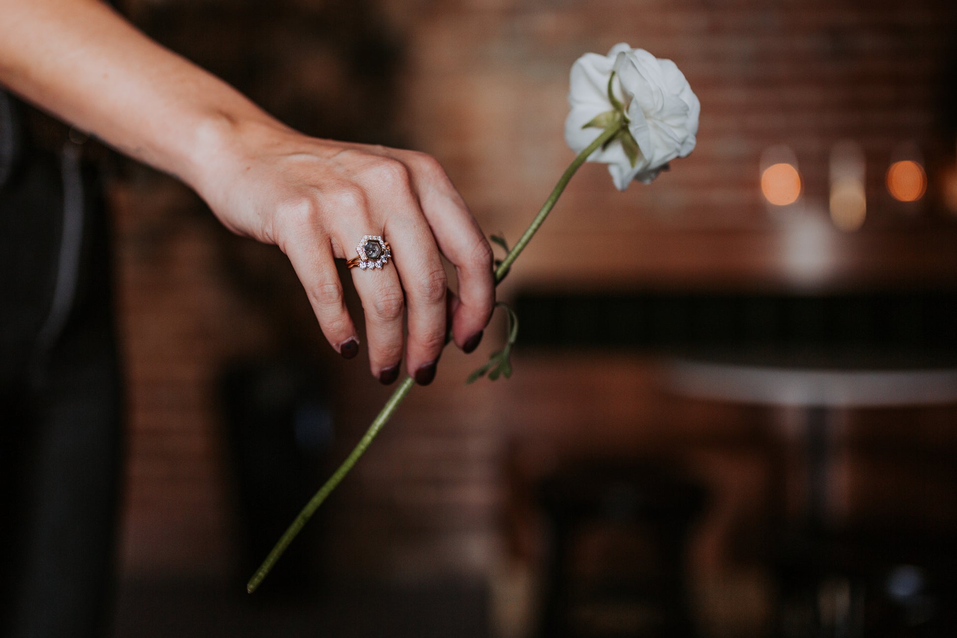Black stone ring on woman's hand, holding a white flower