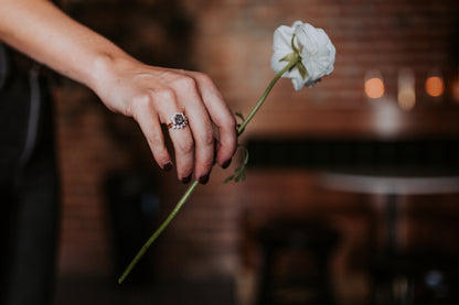 Black stone ring on woman's hand, holding a white flower